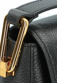Dettaglio di una borsa in pelle nera texturizzata con chiusura e tracolla in metallo dorato, che mette in risalto una finitura liscia e un design raffinato.