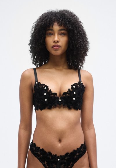 Soutien-gorge en dentelle noire et culotte assortie avec motif floral, ornés d'accents en perles, bretelles réglables et texture semi-transparente.
