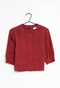 Pull en tricot rouge avec un col rond, des manches trois-quarts et un motif texturé comprenant des designs en vagues ajourés.