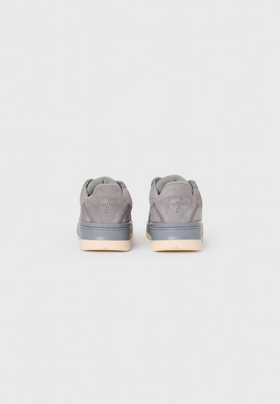 Un paio di sneakers grigie in camoscio viste da dietro, con logo perforato "RP" e suole avorio su uno sfondo chiaro e semplice.