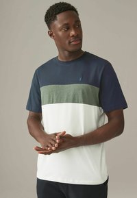 Kortærmet farvede t-shirt med navy, olivengrønne og hvide sektioner. Fremstillet af bomuld med ribbet rund hals og diskret logo.