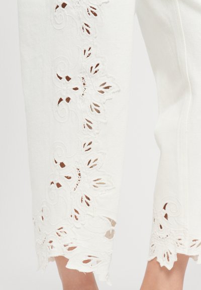 Pantaloni albi scurți cu detalii intricate din dantelă tăiată de-a lungul tivului, evidențiind modele florale și accente ondulate.