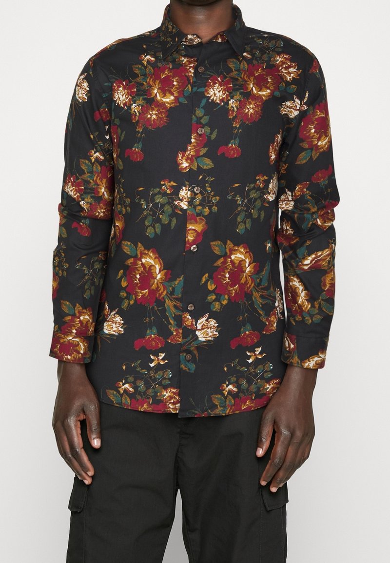Svart långärmad skjorta med blommönster i röd, guld och grön. Har en knappstängning fram och en klassisk krage.