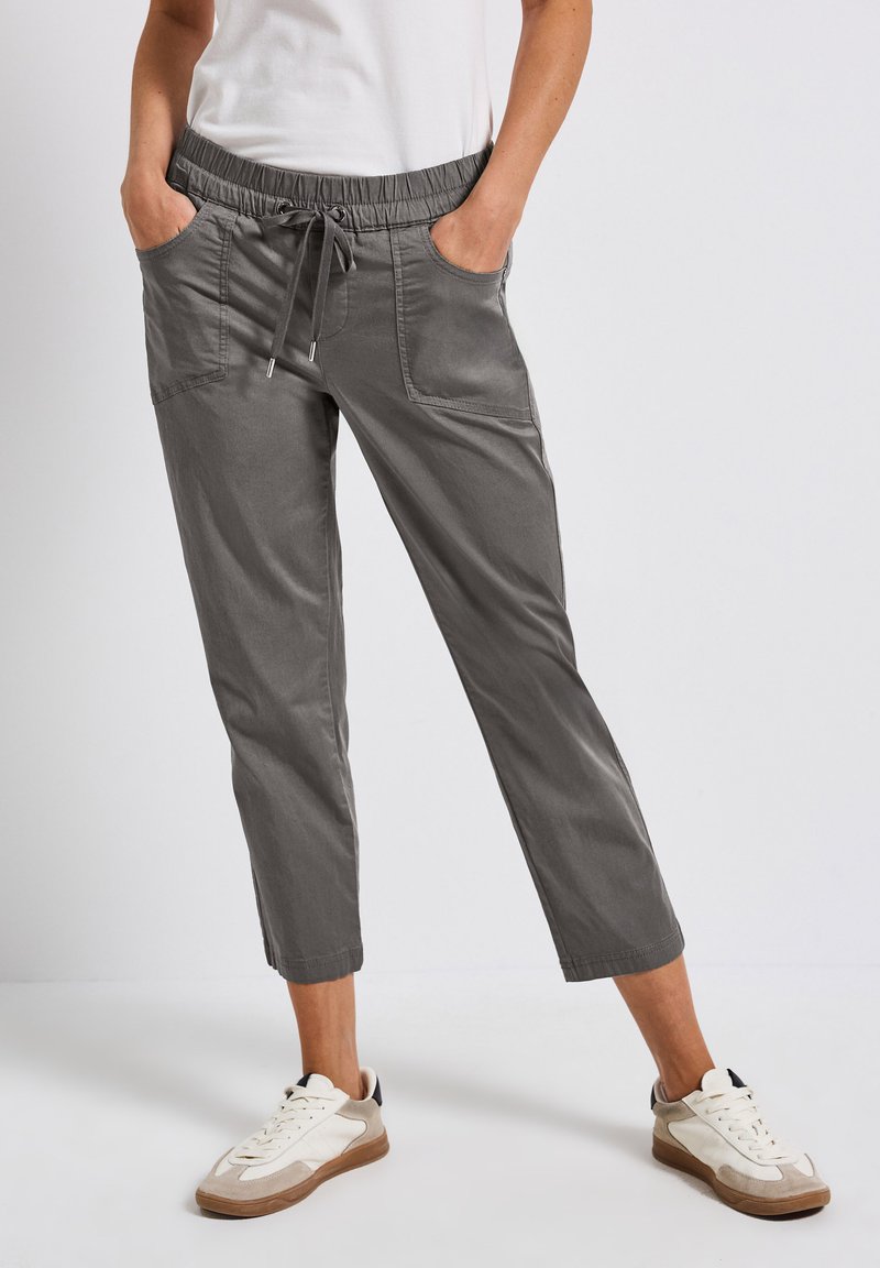 Grijze, cropped broeken met een elastische tailleband en koord, voorzien van zijzakken en een zachte textuur, gecombineerd met witte en beige sneakers.