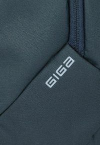 Dunkelgrüner Rucksack aus strukturiertem Stoff, mit einem seitlichen Reißverschluss und "GIGA"-Logo in hellgrau. Kompaktes und funktionales Design.