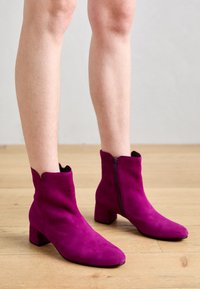 Fuchsia mockaskängor med en kraftig klack, spetsig tå och sidodragkedja. Mjuk textur och scalloped öppning.