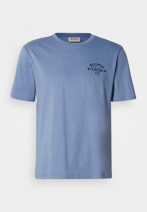 Camiseta azul claro hecha de algodón suave, con cuello redondo, mangas cortas y un pequeño logo negro en el frente.