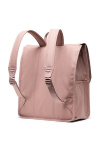 Mochila rectangular rosa hecha de tela suave. Presenta correas acolchadas, bolsillo lateral y tapa superior. Costuras simples y acentos texturizados en las correas.