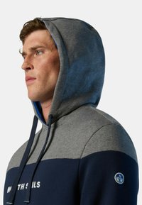 Felpa con cappuccio grigia e navy con interno blu, caratterizzata da un logo sulla manica e design a pannelli contrastanti. Tessuto testurizzato.