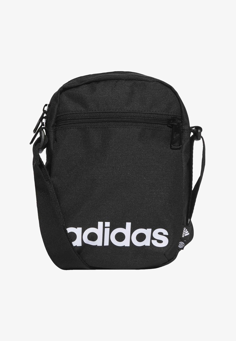 Bolsa cruzada de tela negra con cierre de cremallera, que presenta un gran logo blanco de "adidas" y una correa ajustable. Forma rectangular compacta.