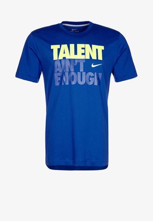 Camiseta de manga corta azul hecha de tela suave. Presenta un texto impreso en negrita en amarillo y gris: "EL TALENTO NO ES SUFICIENTE." Logo de Nike presente.