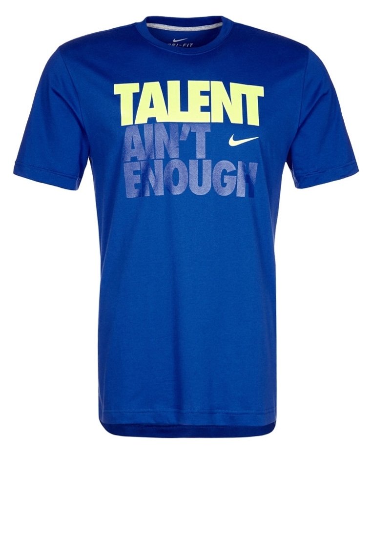Blå kortärmad t-shirt i mjukt tyg. Har fet tryckt text i gult och grått: "TALANG ÄR INTE TILLRÄCKLIG." Nike-logga närvarande.