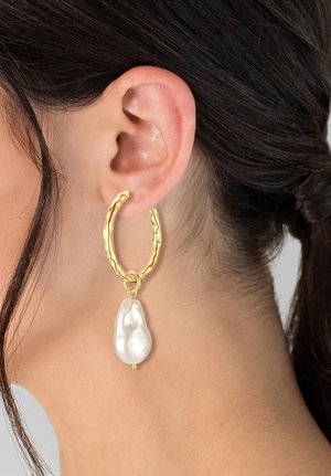 Orecchini a cerchio in oro con un design testurizzato, caratterizzati da una grande goccia di perla bianca irregolare al centro.