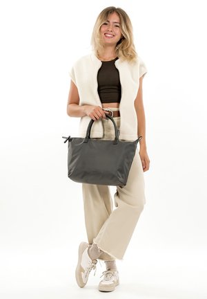 Graue Tragetasche aus glattem Stoff mit zwei Griffen, die eine strukturierte Form und ein minimalistisches Design aufweist, kombiniert mit einem cremefarbenen Pullover und beigen Hosen.
