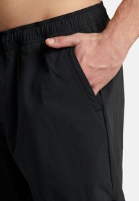 Black lightweight shorts with an elastic waistband and a side pocket. Fabric appears smooth and slightly crinkled, designed for comfort and mobility.