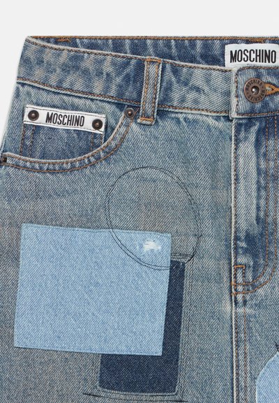 Jeans i denim med olika nyanser av blått, en sliten finish, lappar med detaljer och varumärkesetiketter vid midjan.