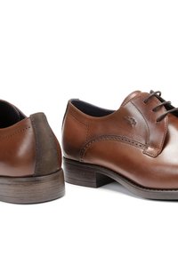 Zapatos de vestir de cuero marrón con acentos de ante en el talón, punta redonda y costuras decorativas. Incluyen cordones planos y una suela con textura de madera.