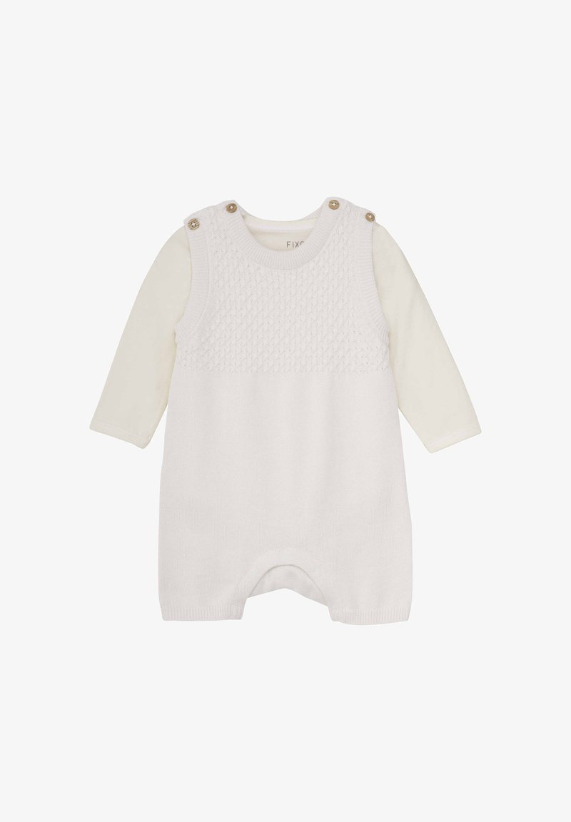 Salopette blanche en maille avec un haut texturé, dotée d'un col rond, d'épaules boutonnées et d'une chemise crème à manches longues en dessous.