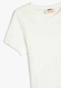 Hvid kortærmet T-shirt med ribbet tekstur og rund halsudskæring. Har et mærke med teksten "Koton Kids." Enkelt design, uden mønstre.