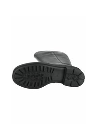 Bota de cuero negra con puntera redondeada y suela de goma texturizada que presenta un patrón antideslizante. La parte superior se extiende más allá del tobillo.