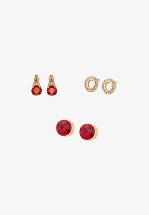 Trzy pary sztyftów do uszu: złote z czerwonymi kamieniami i małymi białymi kryształami w kształcie wież, złote owalne koła z białymi kryształami oraz proste okrągłe czerwone kamienie.