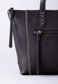 Dark brown leather tote bag with cream stitching detail, zippered pocket, and matching leather handles. Smooth texture, structured shape.