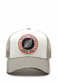 Cappellino trucker bianco e beige con un patch ricamato rotondo che presenta un design a foglia, bordato da un cerchio rosso e dalla scritta "SWEET PANTS SINCE 1982".