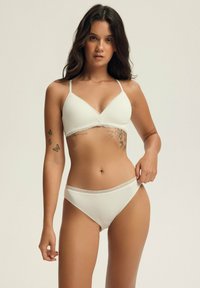 Biały, prążkowany zestaw bikini z trójkątnym biustonoszem z koronkowym wykończeniem oraz dopasowanym, niskim dołem. Gładka tekstura, minimalistyczny design.