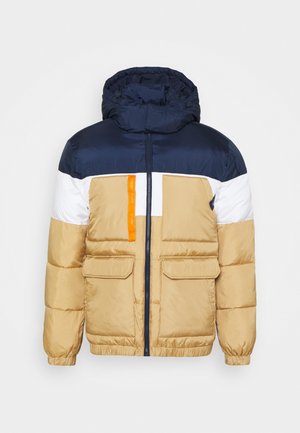 Giacca imbottita con sezione superiore blu navy, pannelli bianchi e beige, cerniera frontale, cappuccio e due tasche frontali con un piccolo accento arancione.