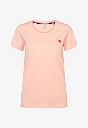 Heleroosa lühikeste varrukatega naiste puuvillane T-särk ümmarguse kaelusega ja vasakul rinnal väike punane tikitud U.S. Polo Assn. logo.