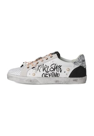 Witte lage sneaker met beige veters, zwarte glinsterende hiel, gespijkerde neus en de tekst "KARL STATE OF MIND" aan de zijkant.