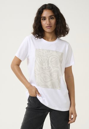 Camiseta de algodón blanca que presenta un gran y sutil estampado floral en beige y la palabra "FLOWERS" bordada en blanco en la parte frontal.
