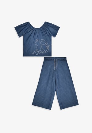 Ensemble deux pièces en denim bleu avec un top court épaules dénudées avec motif chat brodé et pantalon large court avec taille à cordon.