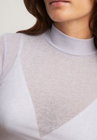 Ljuslila topp med hög hals, gjord av strukturerad, genomskinlig tyg, med triangulära former och en slät finish.