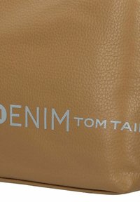 Sac en cuir tan avec une surface texturée, portant "DENIM" en lettres blanches en gras et "tom tailor" en plus petit en dessous.