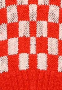 Tessuto lavorato a maglia rosso e bianco caratterizzato da un motivo a scacchiera con quadrati solidi alternati e una superficie testurizzata.