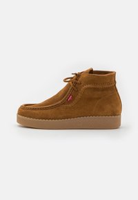 Stivali alla caviglia in suede marrone con punta rotonda, cuciture a contrasto e suola in gomma texturizzata. Presenta una chiusura con lacci corti.