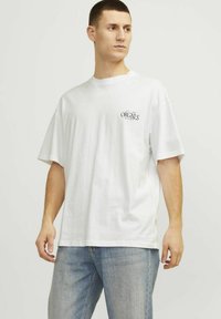 Hvid bomulds T-shirt med korte �ærmer, rund halsudskæring og et lille sort "ORGNLS" print på venstre brystområde. Casual pasform, glat tekstur.