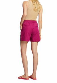 Magenta kraťasy s elastickým pasem, dvěma zadními kapsami a volným střihem, doplněné béžovým ribbed tílkem a růžovými sandály.