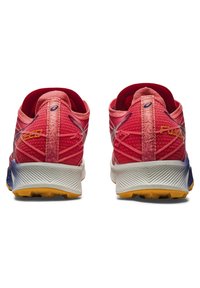 Red athletic shoes with mesh upper, reinforced heel, and rubber outsole. Features gradient color from dark blue to yellow, with branding accents.