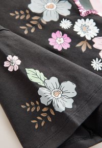 Svart tyg med blommigt mönster som innehåller ljusblå, rosa och vita blommor. Detaljerat med gröna blad och subtila mönster. Mjuk textur.