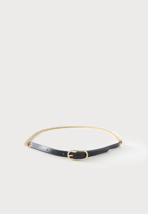 Ceinture en cuir noir avec boucle ovale dorée et fine chaîne dorée attachée sur un fond clair.