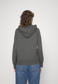 Sweat à capuche gris en matière douce avec capuche ajustable par cordon, poignets et ourlet côtelés. Porté avec un jean taille haute bleu clair.