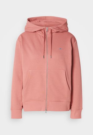 Pink zip-up hoodie made of soft fabric, featuring a drawstring hood, two front pockets, and ribbed cuffs and hem. Small logo on chest.