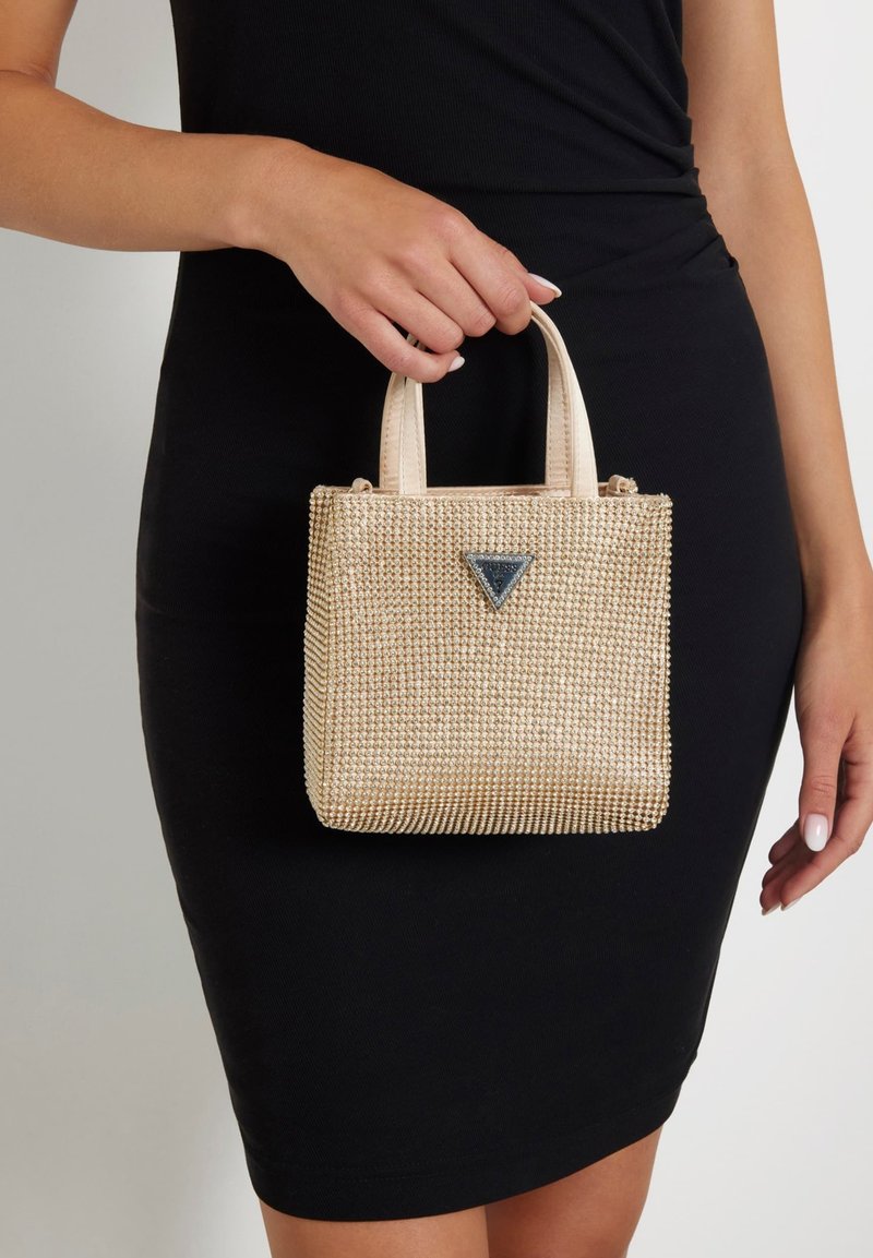 Borsa a mano con perline dorate, dalla forma strutturata, con due manici corti e un emblema triangolare sul fronte. Interno liscio e superficie texturizzata.