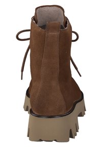 Hnědá semišová kotníková bota s kulatou špičkou, robustní béžovou podrážkou a zavazováním šněrovadelek vzadu. Texturovaný svršek s měkkou vnitřní podšívkou.