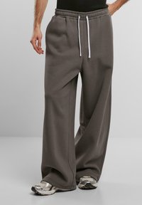 Pantaloni della tuta larghi grigi realizzati in morbido tessuto, con una vita elasticizzata e coulisse e tasche laterali. Abbinati a sneaker argentate.