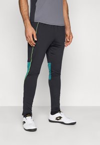 Μαύρο αθλητικό παντελόνι με πράσινες λεπτομέρειες, κατασκευασμένο από ελαστικό υλικό. Διαθέτει εφαρμοστή γραμμή και πλαϊνή λεπτομέρεια σε τιρκουάζ.