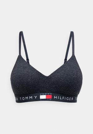 Tumma harmaa bralette, joka on valmistettu teksturoidusta kankaasta. Siinä on ohuet hihnat ja brändätty joustovyö punaisilla, valkoisilla ja sinisillä yksityiskohdilla.