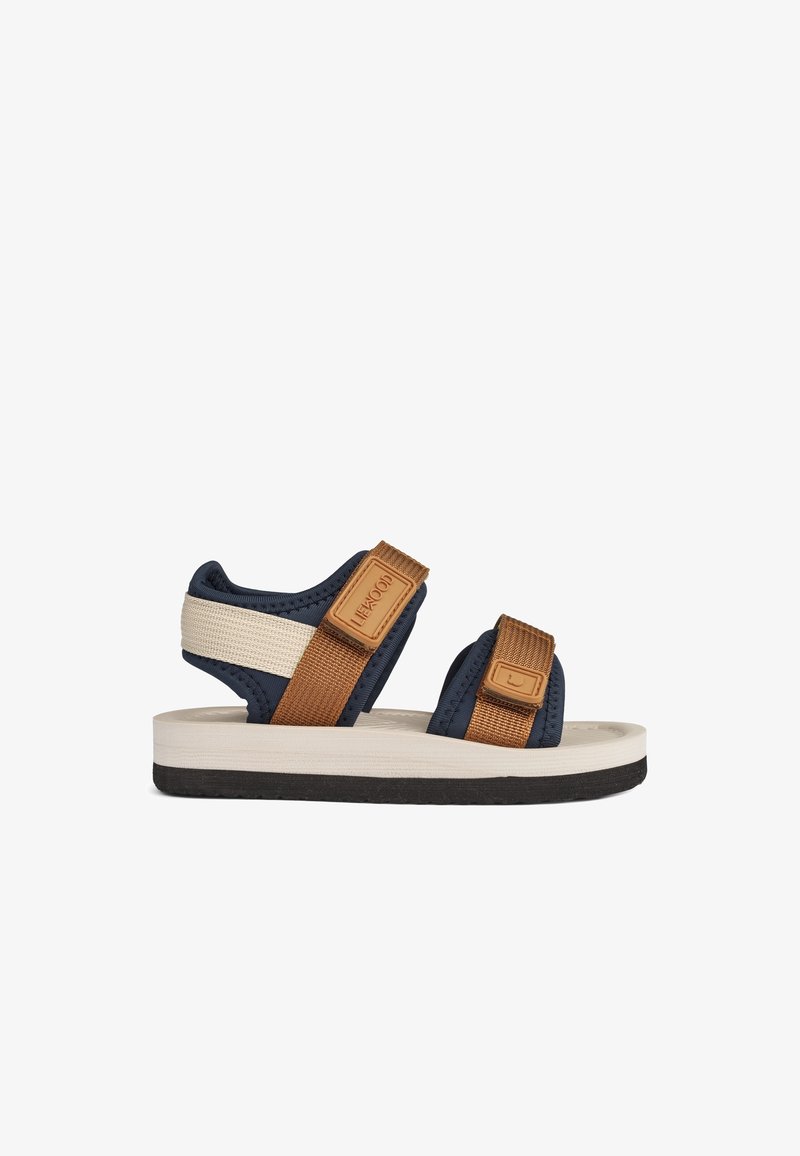 Sandales marine et beige avec brides ajustables, tissu texturé, semelle souple et une semelle intermédiaire blanche contrastante. Adaptées aux temps chauds.